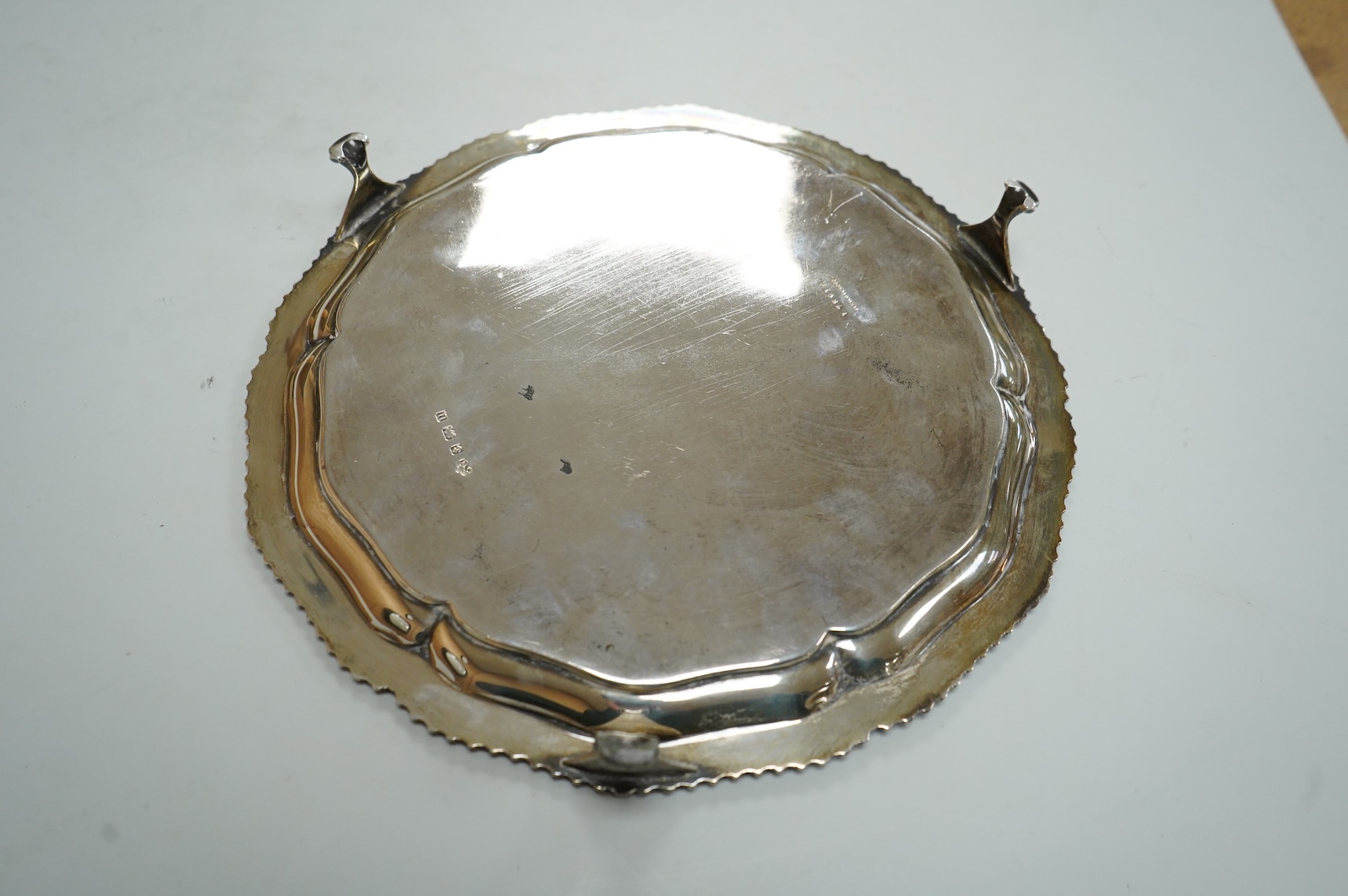 A George V silver salver, by Elkington & Co, of shaped circular form, with engraved crest, on three scroll feet, diameter 26.2cm, 18.7oz.